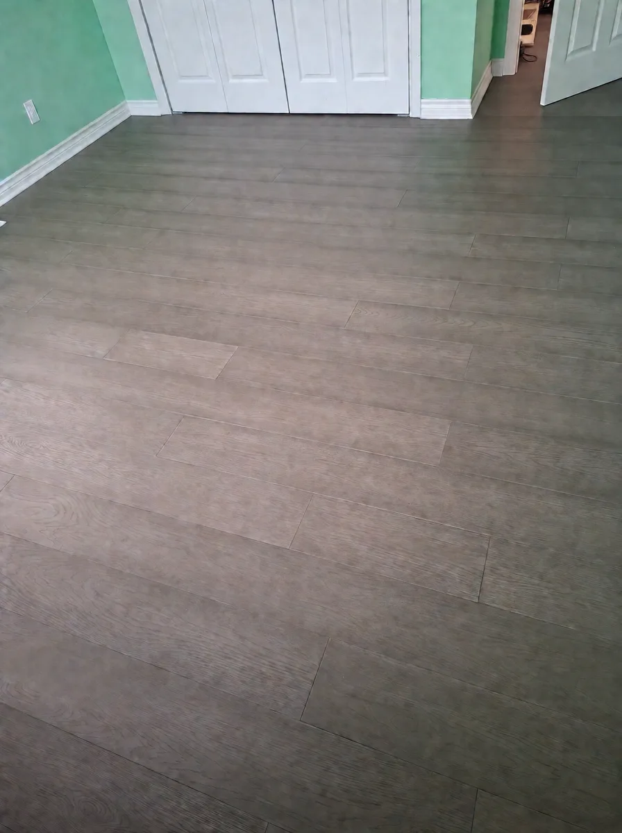 Bedroom with white closet doors and new grey-brown wide-plank oak flooring