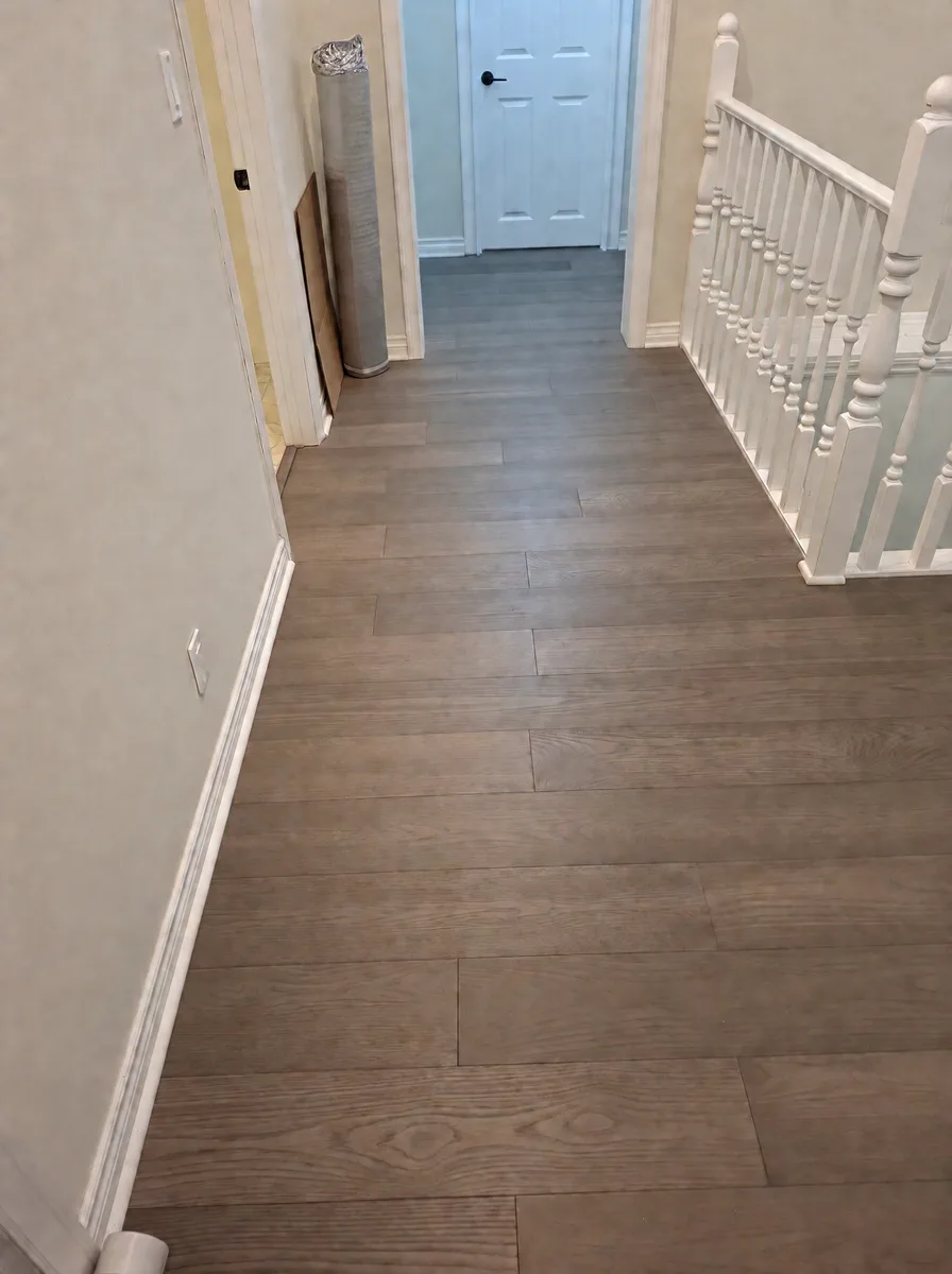 Upstairs hallway with new oak plank flooring leading to a white door past the stair railing