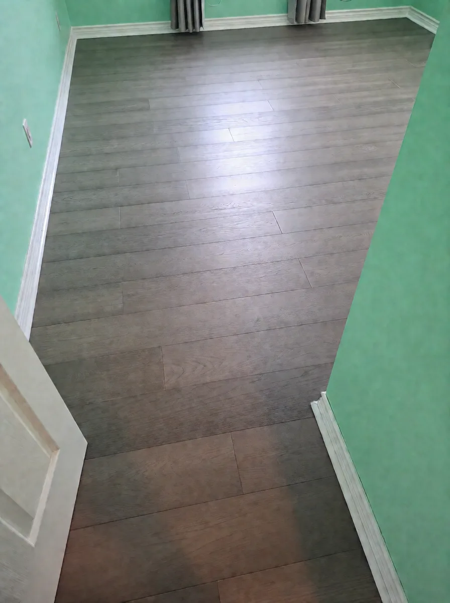 View through a bedroom doorway onto new grey oak plank flooring and mint-green walls