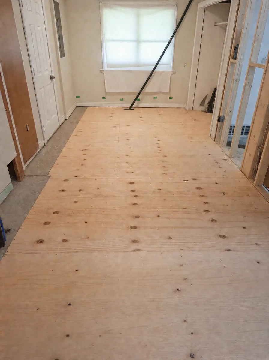 Finished plywood subfloor running to the window beside new stud framing