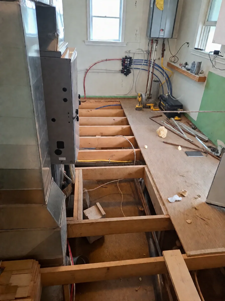Laundry room floor opened to new joists beside the furnace and tankless water heater