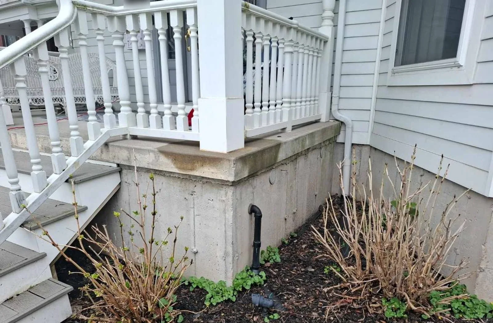 Bare concrete porch foundation before parging