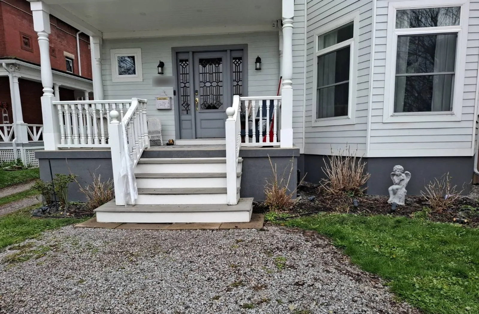 Front porch with white turned-baluster railings, grey composite steps and a charcoal parged foundation skirt