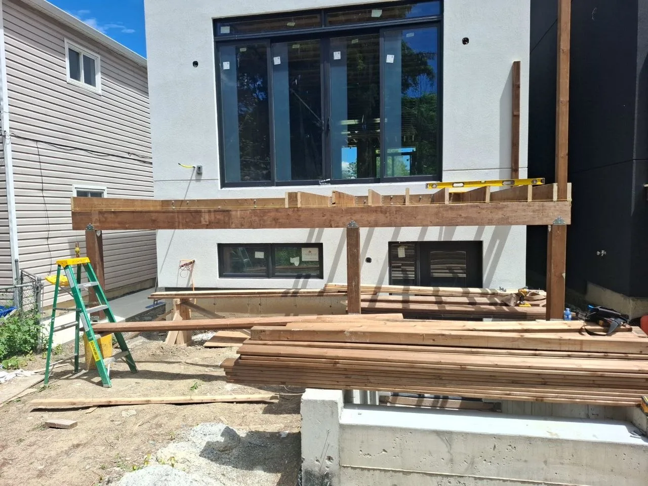 Modern Toronto townhome deck build with natural wood decking and railing — white unit deck framing