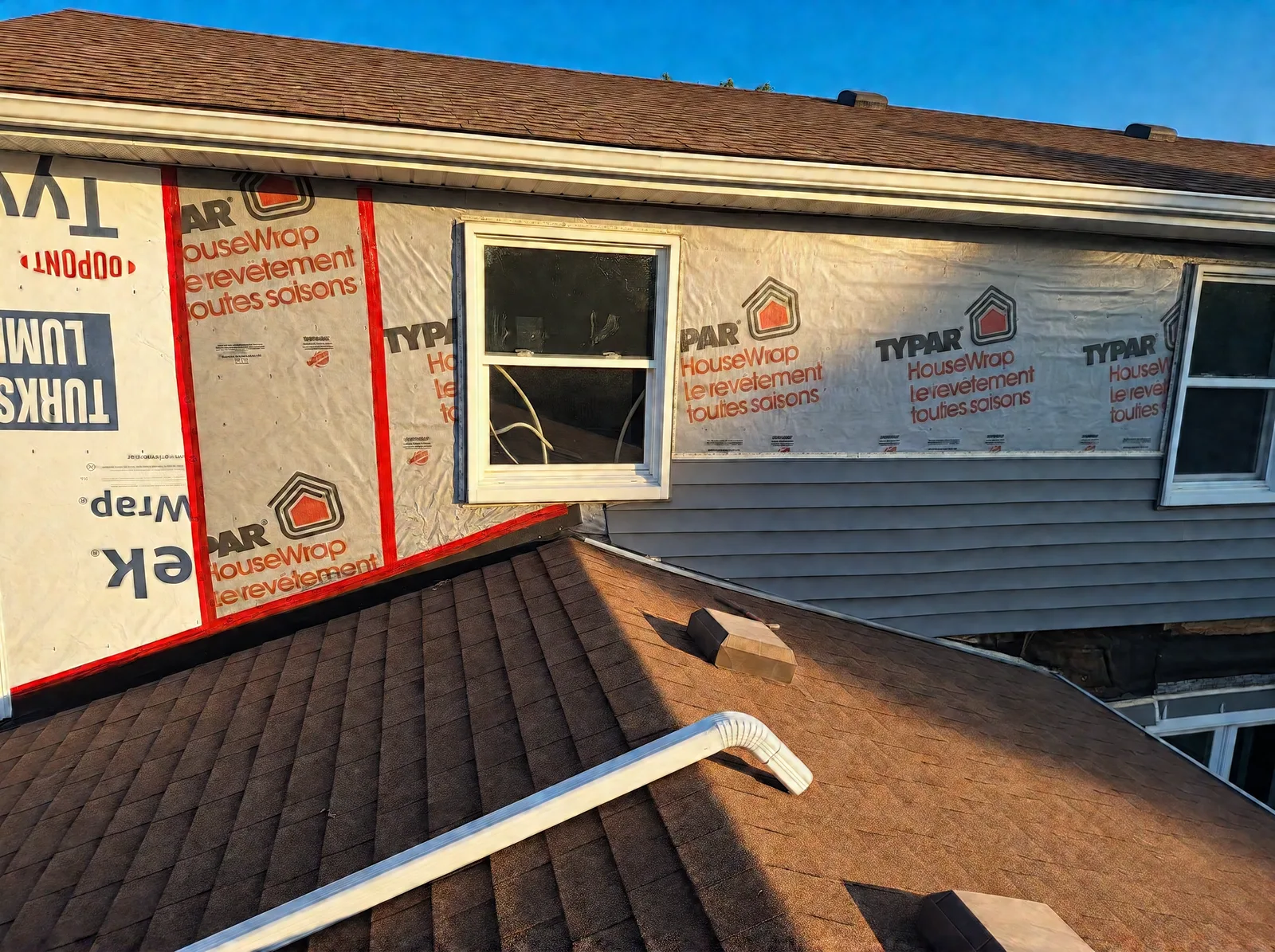 Typar HouseWrap and red seam tape on the wall above a lower roof, around a window