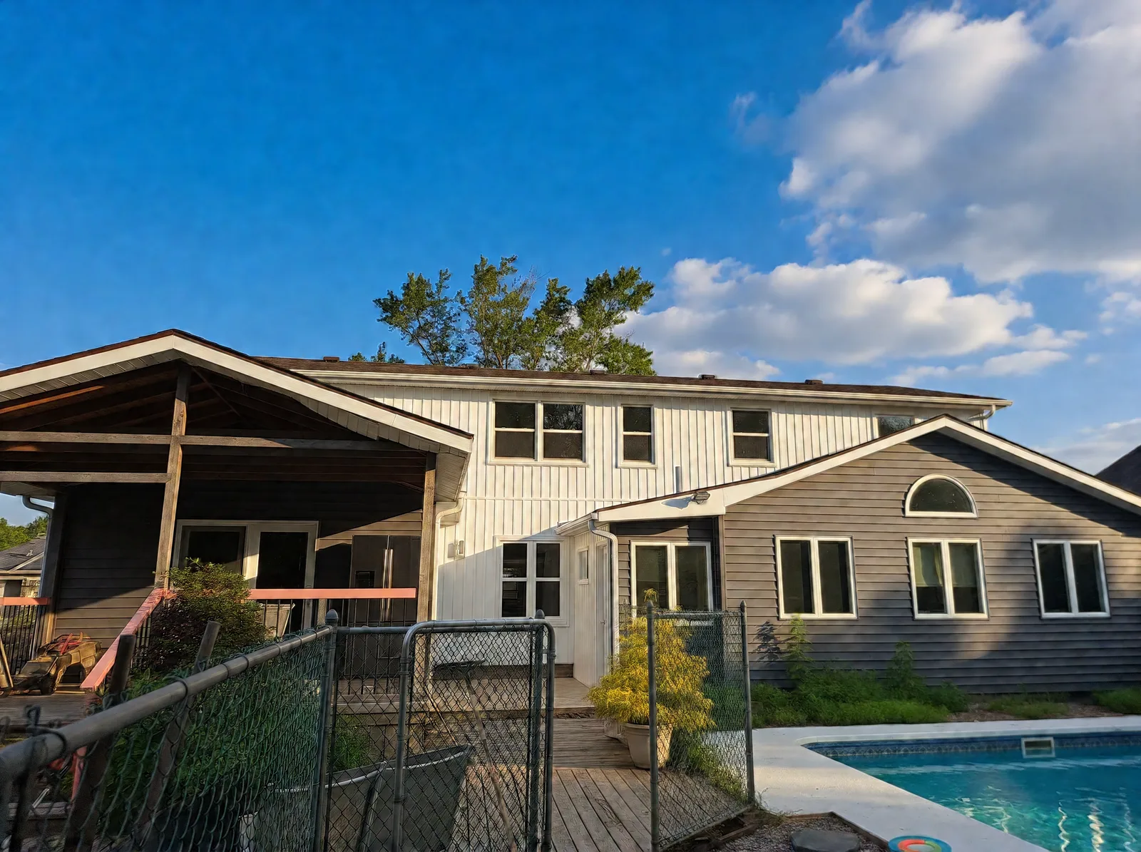 Rear of the home from the pool side, with new white vertical siding on the two-storey section