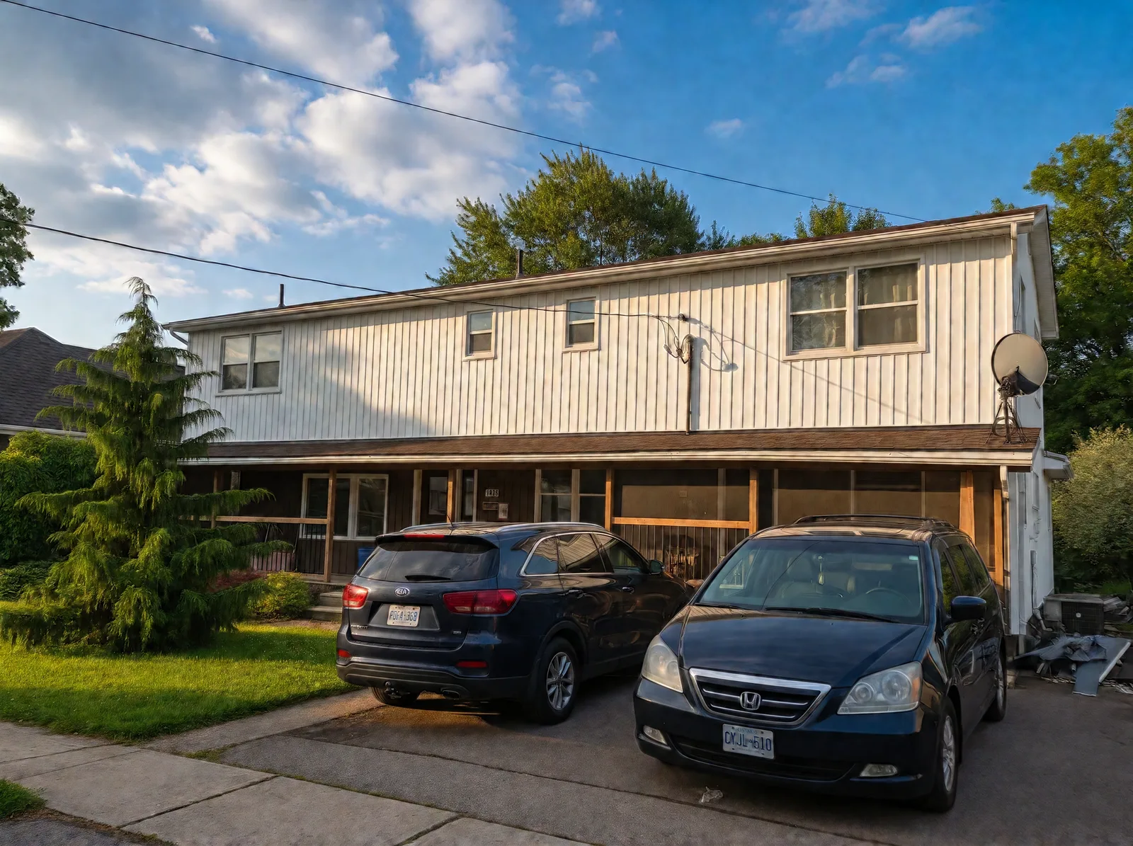 Street view of the finished front with white vertical siding across the upper storey